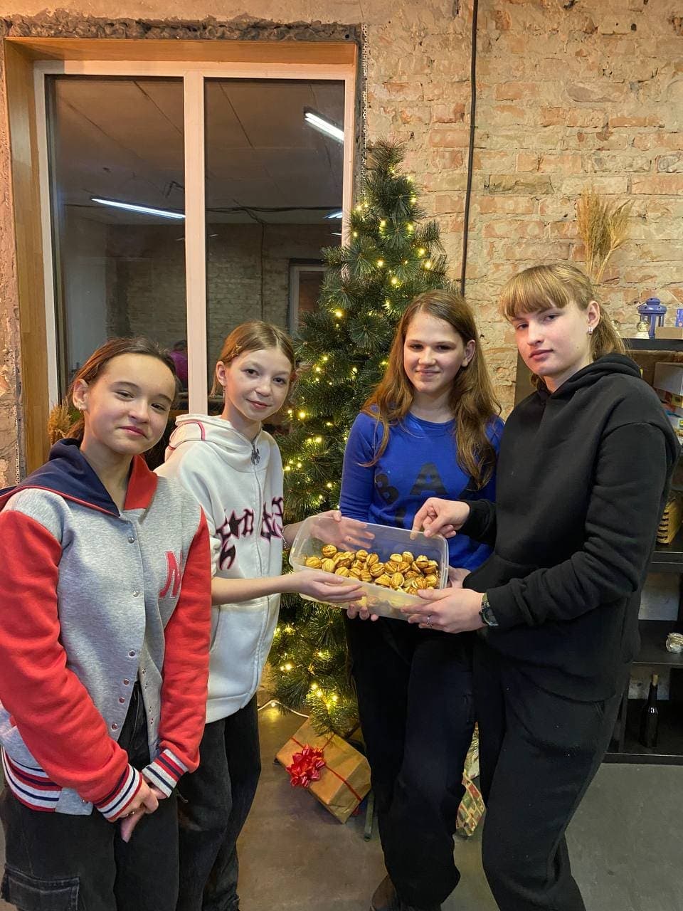 Група підлітків разом тримає ящик з печивом та посміхається